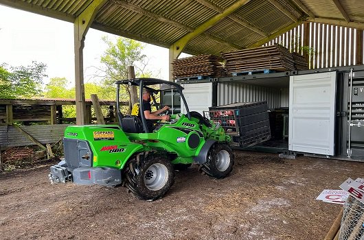 Photo of a tractor loading the storage container with Cowpie show material