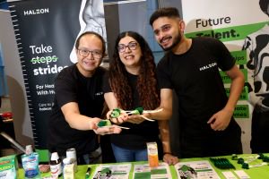 Three people stand behind a promotional stand at an event holding Haleon branded products